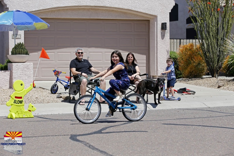 A girl riding a bike in front of a family. 