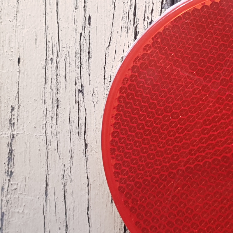 A red reflector post against a gray background. 