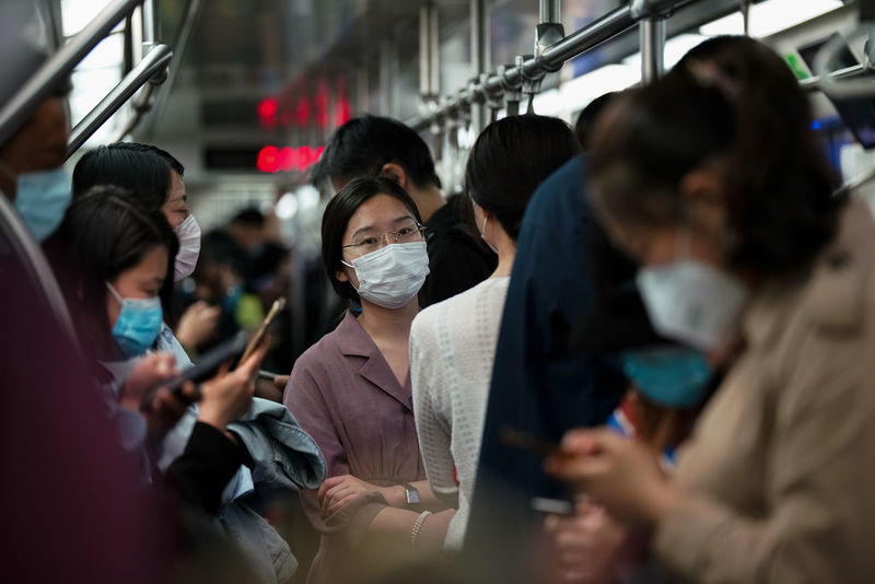 Photo of several people on a subway in masks.