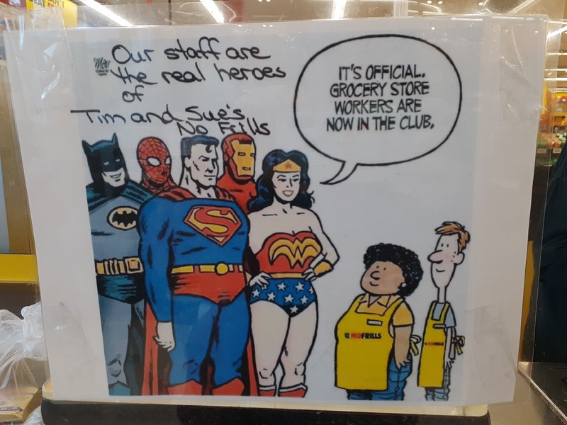 This is a picture of a drawing made depicting Superman, Superwoman, Spider Man, Iron Man, and Batman talking to a pair of grocery store workers. A speech bubble above the superheros reads "Its official. Grocery store workers are now in the club."
