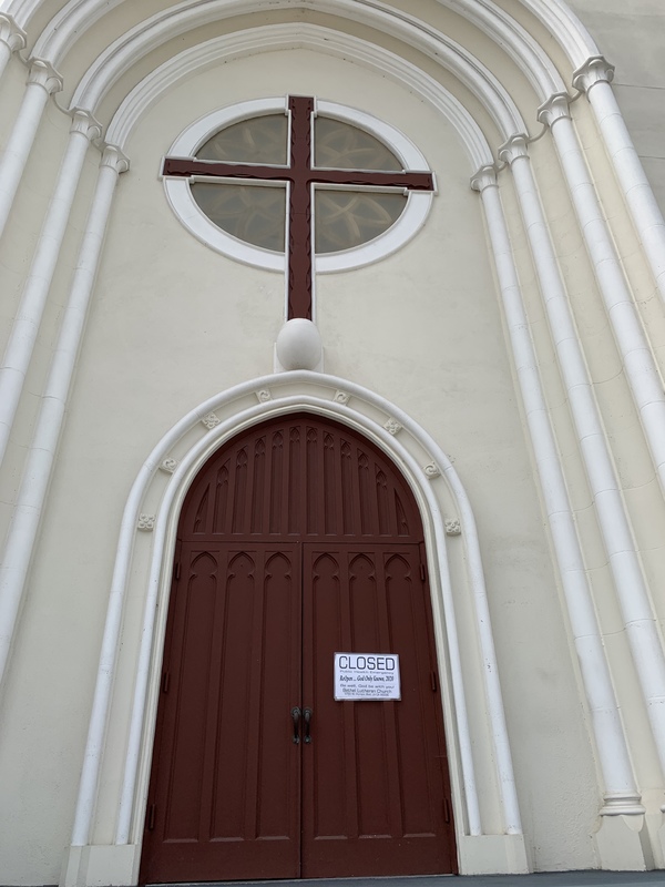 The front of a Church door with a white sign on it.