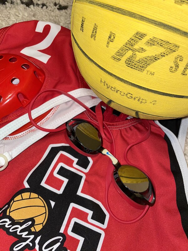Red sports jersey with goggles and yellow water polo ball.