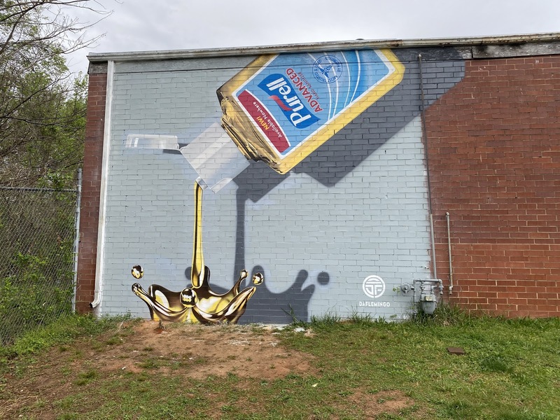 On the side of a building is a mural of Purell hand sanitizer; the sanitizer symbolizes liquid gold. 