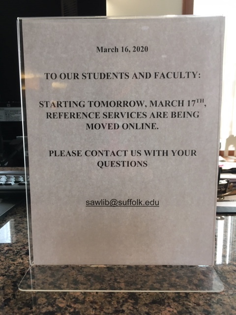 Sign on Suffolk University Sawyer Library Reference Desk with text saying, "March 16, 2020; TO OUR STUDENTS AND FACULTY: STARTING TOMORROW, MARCH 17TH, REFERENCE SERVICES ARE BEING MOVED ONLINE. PLEASE CONTACT US WITH YOUR QUESTIONS; sawlib@suffolk.edu"