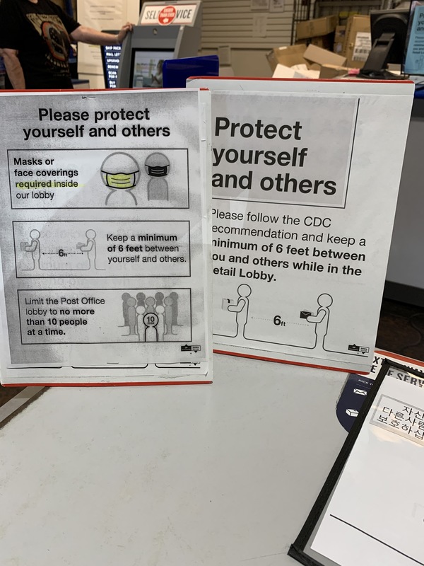 Image of signs in a post office that say please protect yourself and others. Masks or face coverings are required inside our lobby. Keep a minimum of six feet between yourself and others. Limit the Post Office lobby to no more than 10 people at a time.