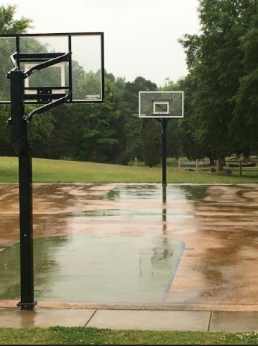 Outdoor basketball court with both standards missing basketball hoops and nets.