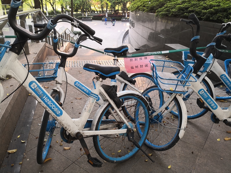 Bikes that are blocking an entrance to stairs. A pink piece of paper is taped on the blockade that says translated to English: "Control the epidemic temporary closure".
