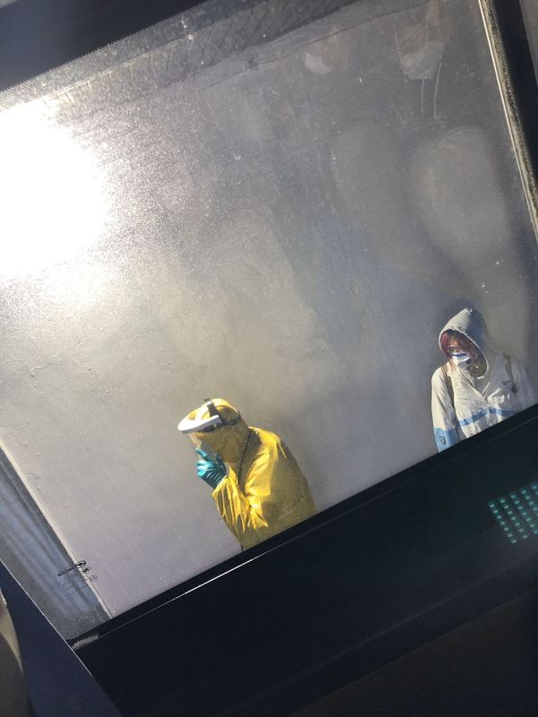 A person in a yellow hazmat suit and a person in a white work suit. 