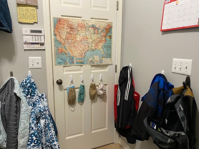 Masks and backpacks hanging on a door. 