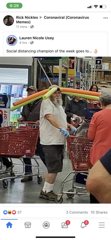 A man is ensuring those around him are keeping their distance by wearing a hat with pool noodles attached to it. 