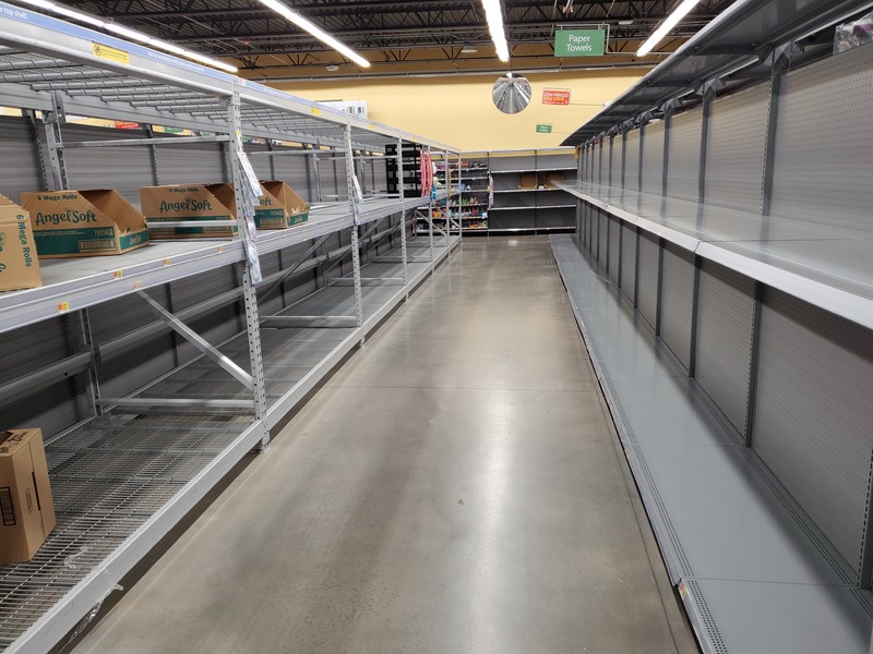 An aisle with empty shelves on both sides. 