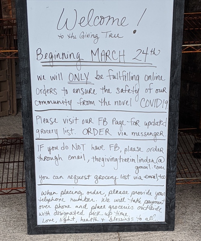 A whiteboard sign in front of a store giving information to its patrons about only doing online orders and how to do an online order through Facebook or email. 