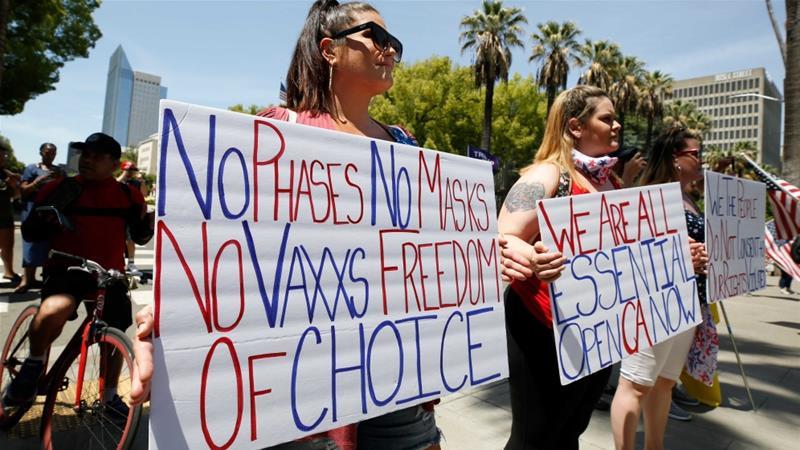 Image of two women holding signs, one of which says no phases, no masks, no vaxxs, freedom of choice.
