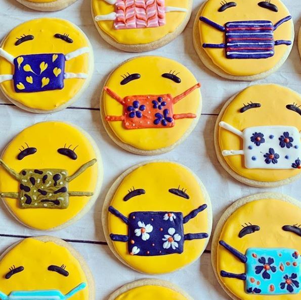 Multiple cookies decorated as smiley faces with masks on.