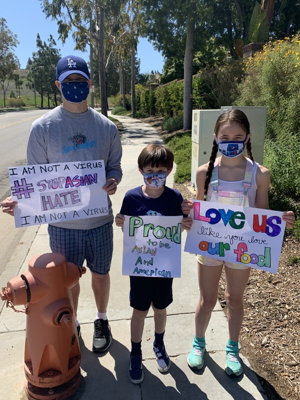 This is a picture of an Asian man and two children holding signs that urge the reader to help combat attitudes of Asian hate in wake of the COVID-19 Pandemic. 