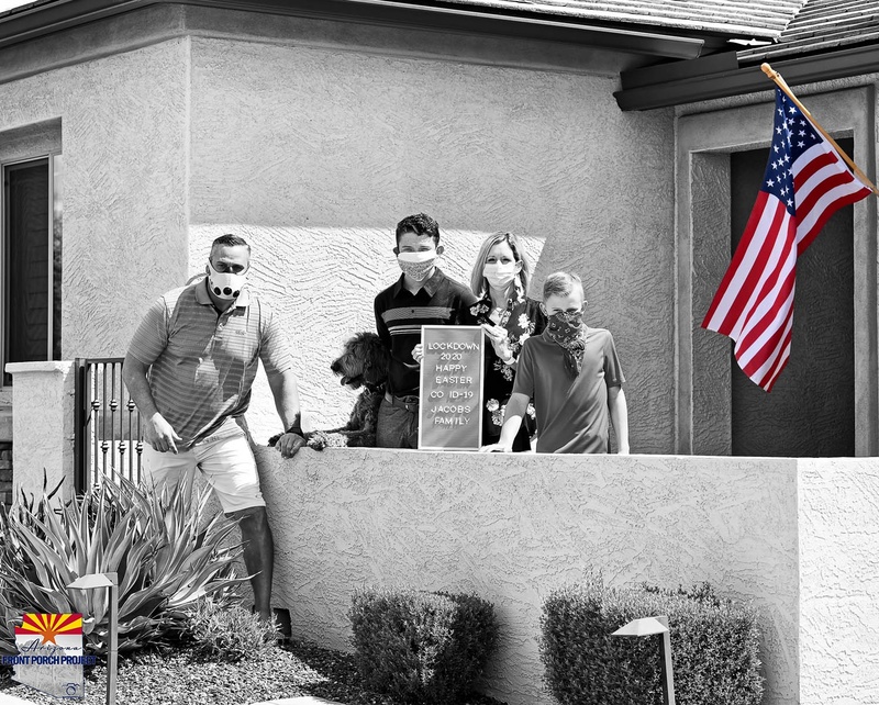 A family poses in front of a house with an American flag. 