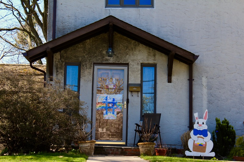 The front of a house has rainbow drawings and a blue hashtag on the front door. 