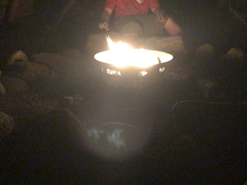 This is a picture of a group of people gathered around a fire outdoors. 