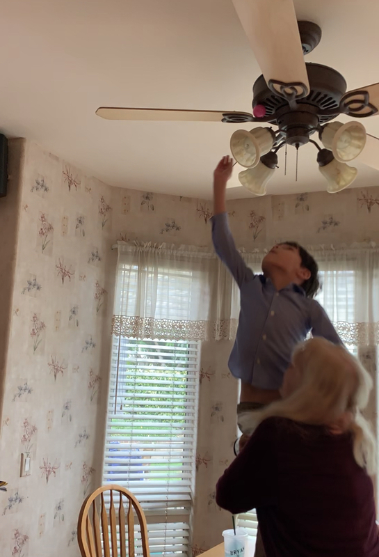 Screenshot of a woman holding a child up to the ceiling. 