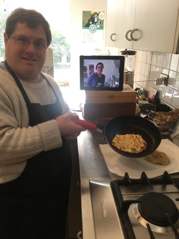 A man cooking on a video call with a woman.