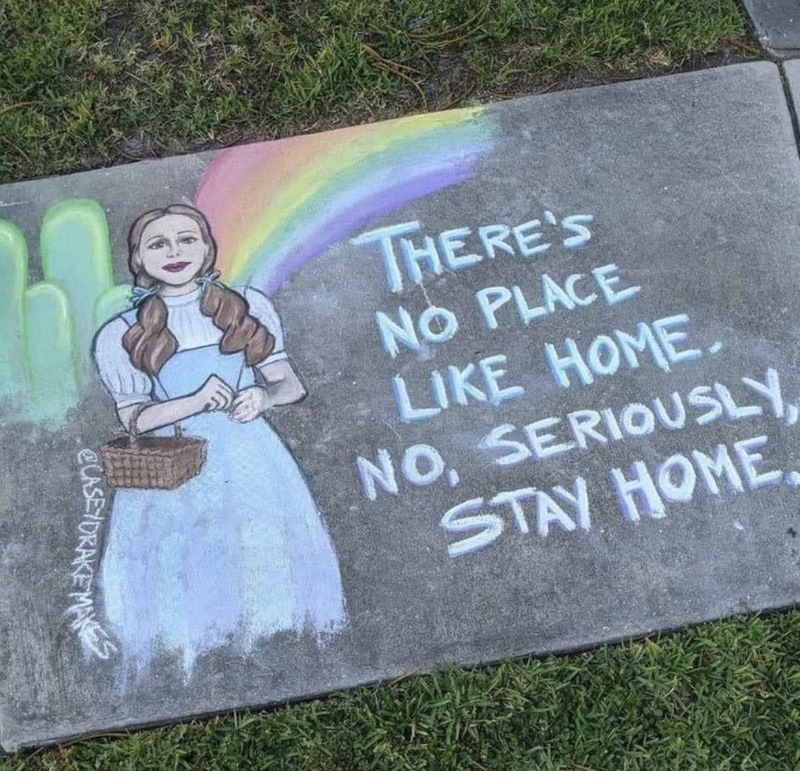 Sidewalk art of a girl with a basket and writing that says "there's no place like home. No, seriously, stay home."