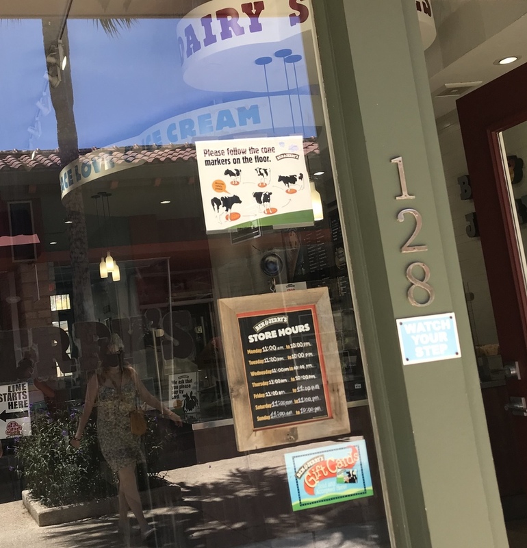 This is a picture taken of a sign in the window of an ice cream shop, which encourages people to shop while adhering to social distancing standards. 