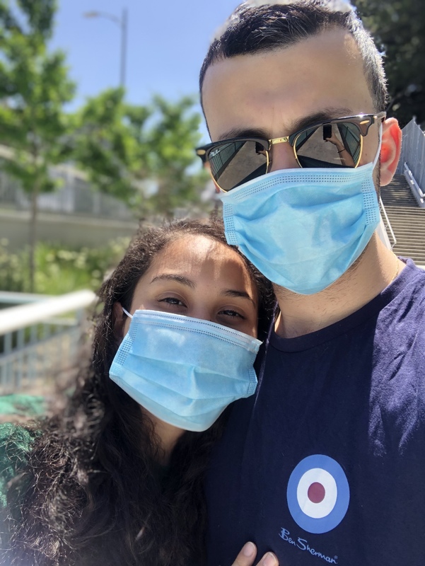 Two people taking a selfie wearing blue medical face masks.