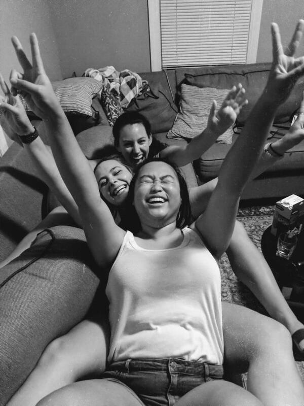 This is a picture taken of three women sitting on a couch and laughing. 