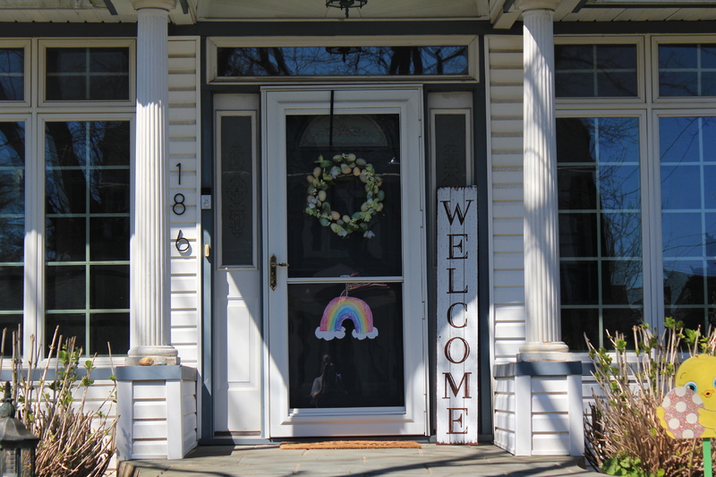 A residential house with a rainbow on the front screen door.