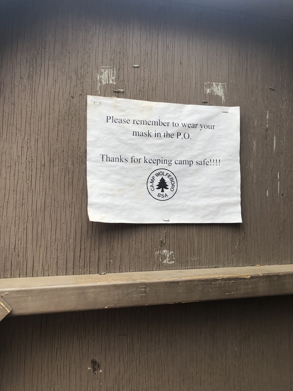 This is a picture taken of a sign at a Boy Scout Camp which urges people to remember to wear their face masks. 