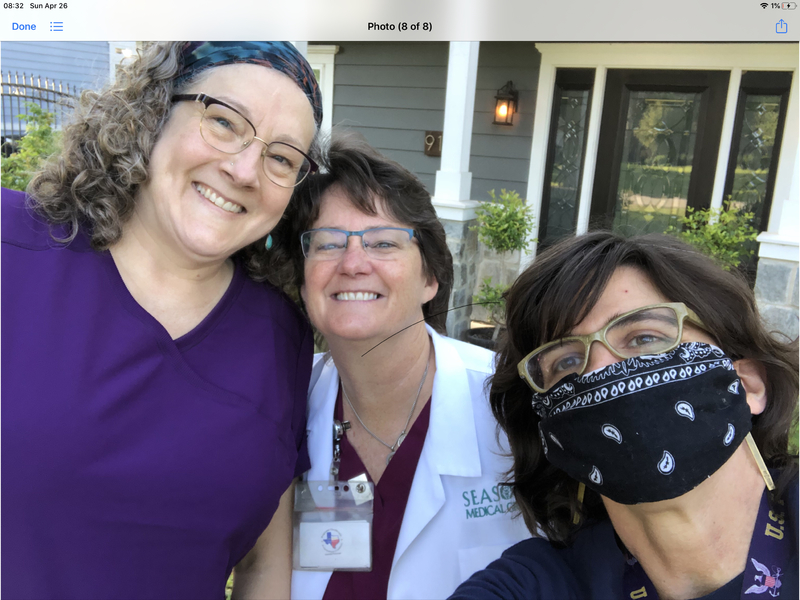 three women in glasses smiling at the camera one in a black mask