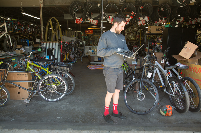 A person holding a laptop in a bike store.