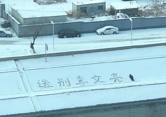 A street covered in snow that has someone writing in the snow: "Farewell to Li Wenliang".