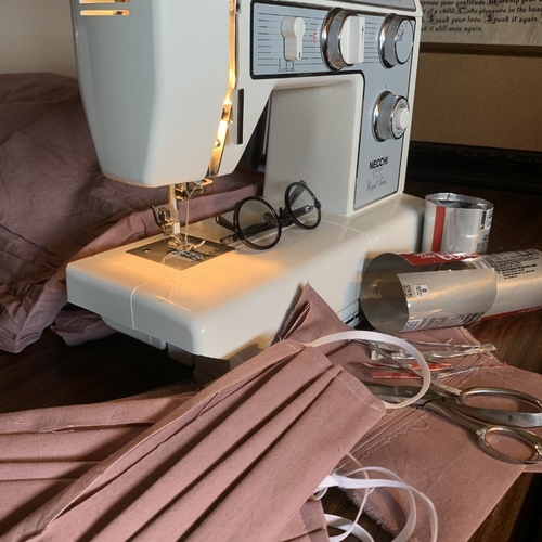 A sewing machine with face masks around it. 