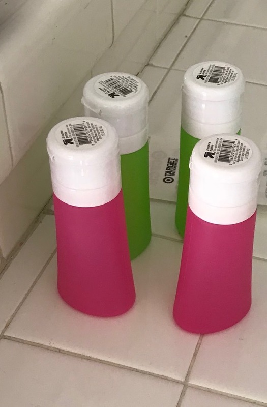 four hand sanitizer bottles, two green and two pink. 