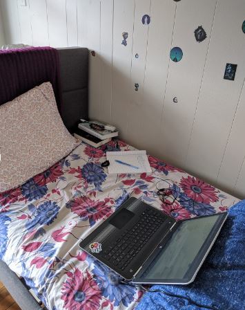 A room with a bed in it. On top of the bed is a laptop. 