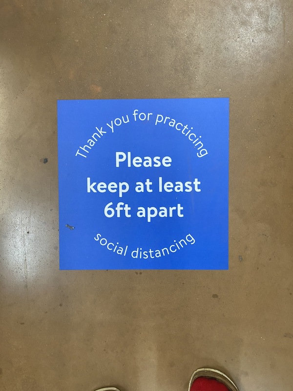 A sign on a floor that says "Please keep at least 6ft apart."