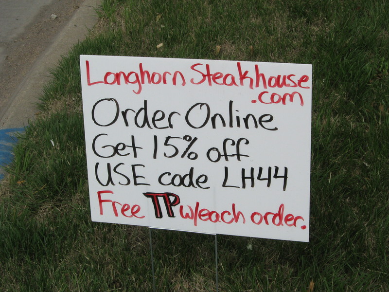 A hand written black and red sign telling about discount codes for a stake house