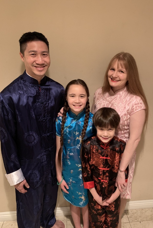 Family with father, mother, daughter, and son smiling in silk kimonos for Chinese New Year.