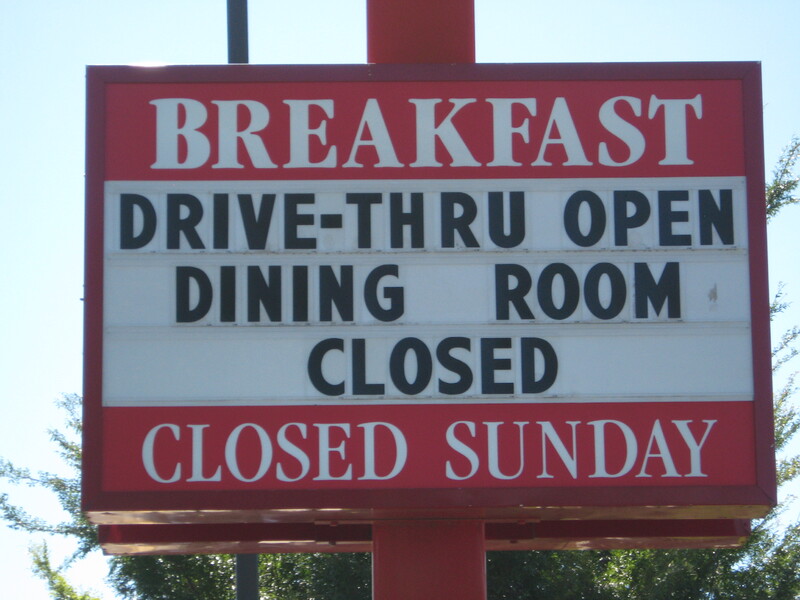 Sign outside of a restaurant saying "Drive-thru open, dining room closed". 