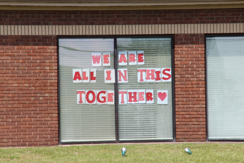 Signs in a window reading "We are all in this together".
