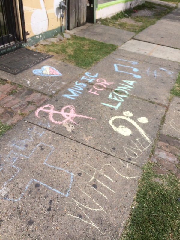 "Music for Leona" written on the sidewalk with chalk. 