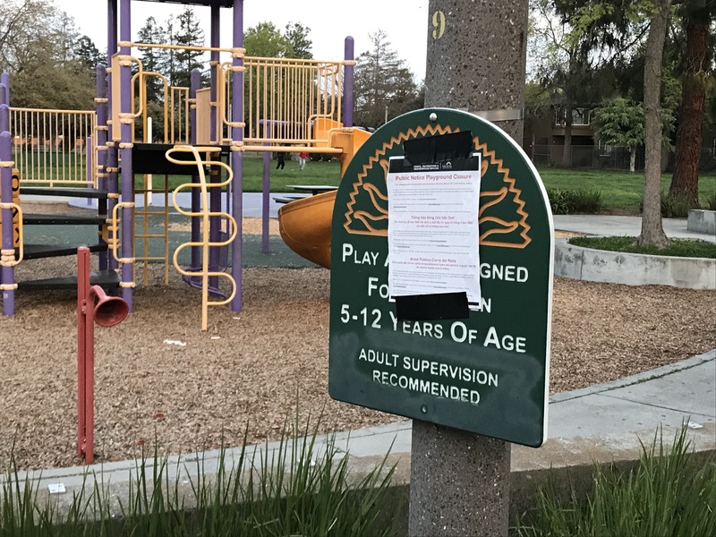 A public notice is taped over a sign to a playground. 
