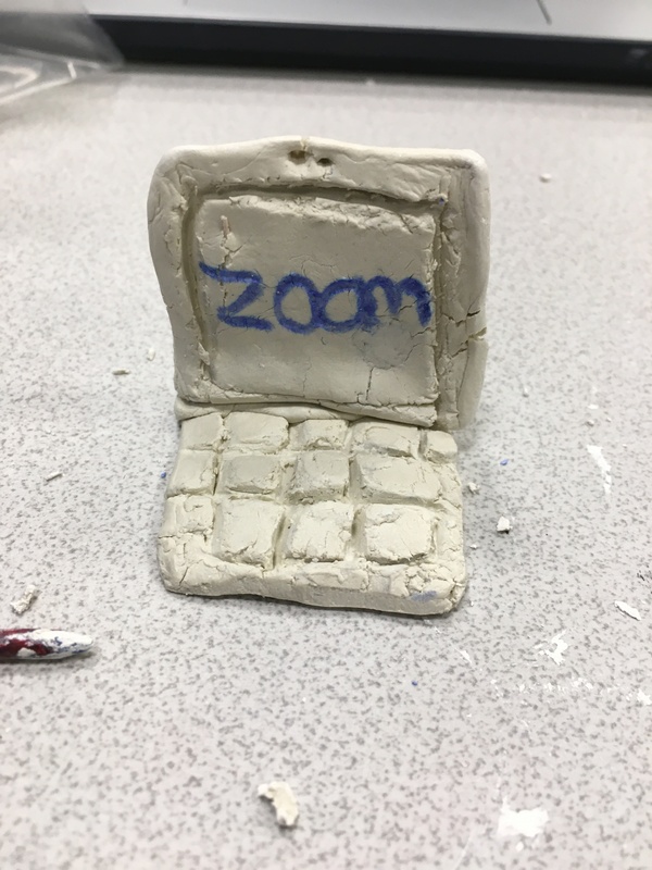 This is a picture of a small laptop that was created out of clay, with the word "Zoom" written on the screen in blue. 