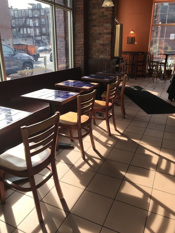 Empty tables and chairs facing a window in a café.