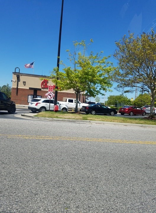 A line of cars outside a drive through fast food restaurant. 
