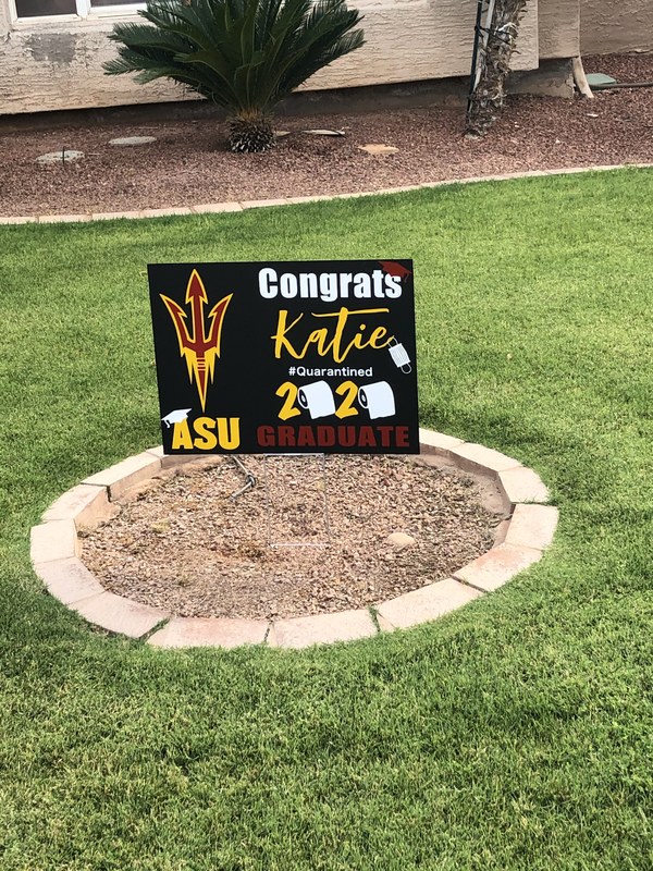 A black, yellow and red lawn sign of graduation. 