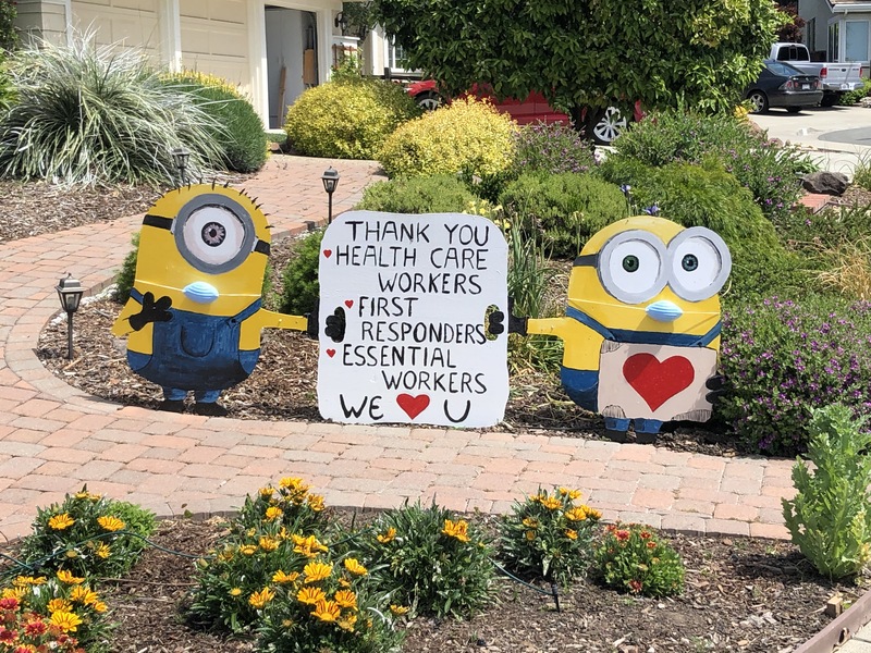This is a picture of a sign in a front yard being held by two minions thanking healthcare workers. 
