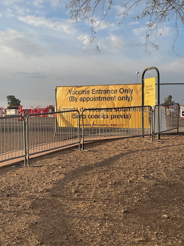 This is a picture of a sign in front of a vaccination area within a parking lot that reads "Vaccine entrance only (by appointment only)."