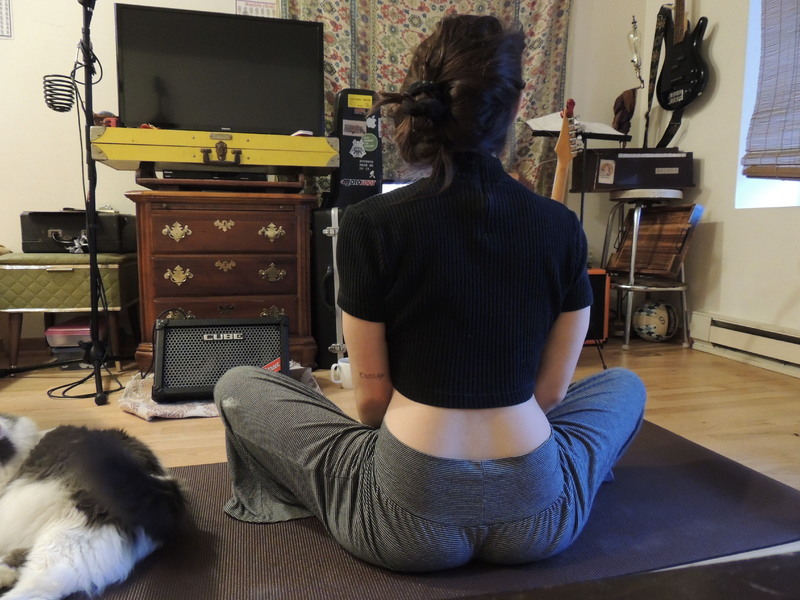 A person sitting on a mat next to a cat. 